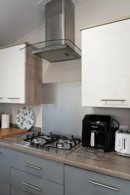 a kitchen with a stove and a microwave at Bittern Lodge: 3BD Retreat in South Lakeland Park in Borwick