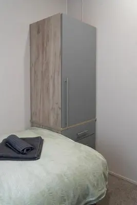 a bedroom with a bed with a large wooden cabinet at Bittern Lodge: 3BD Retreat in South Lakeland Park in Borwick