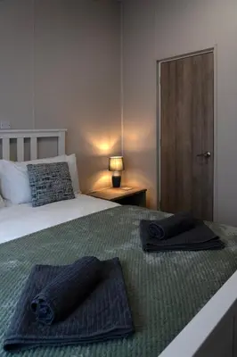 a bedroom with a bed with two towels on it at Bittern Lodge: 3BD Retreat in South Lakeland Park in Borwick