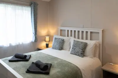 a bedroom with a bed with two towels on it at Bittern Lodge: 3BD Retreat in South Lakeland Park in Borwick