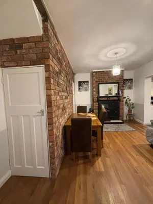 a living room with a brick wall and a table at Birkdale Golf Open Holiday Home in Southport