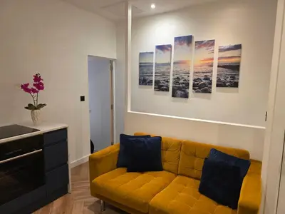 a living room with a yellow couch and paintings on the wall at 2 Bedroom Apartments Near Anfield Stadium - Sleeps 4 per Flat in Liverpool