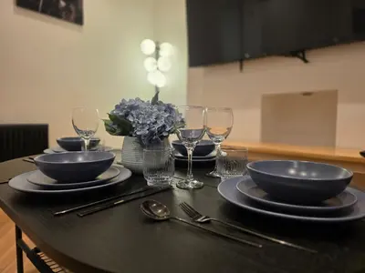 a table with plates and bowls and glasses on it at 2 Bedroom Apartments Near Anfield Stadium - Sleeps 4 per Flat in Liverpool