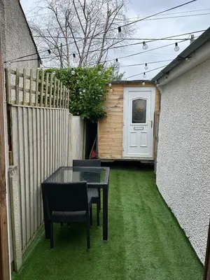 a patio with a table and chairs and a fence at The Telephone exchange very quaint hot tub stay in Scarisbrick