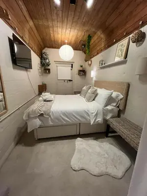 a small bedroom with a bed and a bench at The Telephone exchange very quaint hot tub stay in Scarisbrick