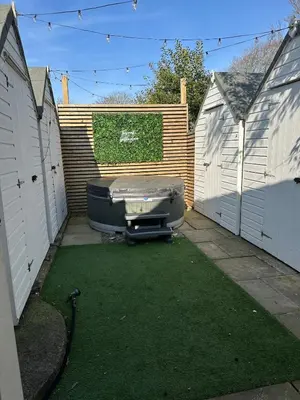 a backyard with a tub and a fence at The Telephone exchange very quaint hot tub stay in Scarisbrick
