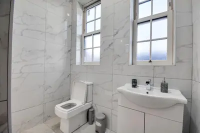 a white bathroom with a toilet and a sink at Cosy Wigan Apartment with Sunny Views in Wigan