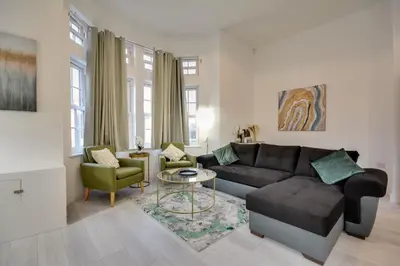 a living room with a couch and a table at Cosy Wigan Apartment with Sunny Views in Wigan