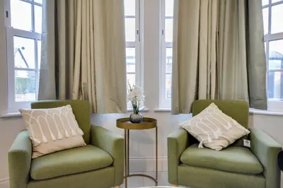 two chairs and a table in a room with windows at Cosy Wigan Apartment with Sunny Views in Wigan