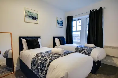 two beds in a room with a window at Wigan - Apartment - Sleeps 6 - Parking in Wigan