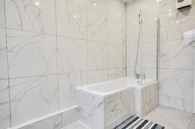 a white bathroom with a tub and marble walls at Wigan - Apartment - Sleeps 6 - Parking in Wigan