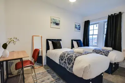 two beds in a room with a table and a desk at Wigan - Apartment - Sleeps 6 - Parking in Wigan