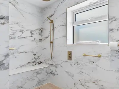 a white marble bathroom with a window and a shower at Newly Renovated Luxury Bungalow Pass the Keys in Ulverston
