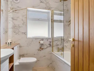 a bathroom with a toilet and a tub and a window at Newly Renovated Luxury Bungalow Pass the Keys in Ulverston