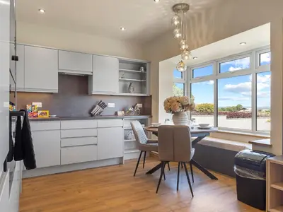 a kitchen with white cabinets and a table with chairs at Newly Renovated Luxury Bungalow Pass the Keys in Ulverston