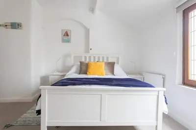 a white bed with an orange pillow on it at Fisherman's Cottage by the sea in Morecambe