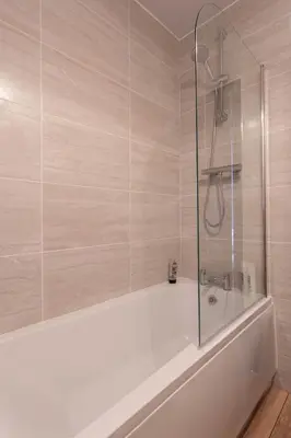 a bath tub with a glass shower in a bathroom at Fisherman's Cottage by the sea in Morecambe