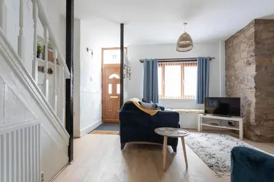 a living room with a blue couch and a tv at Fisherman's Cottage by the sea in Morecambe