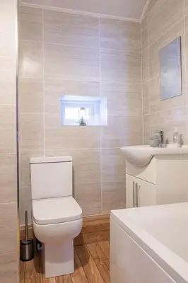 a white bathroom with a toilet and a sink at Fisherman's Cottage by the sea in Morecambe