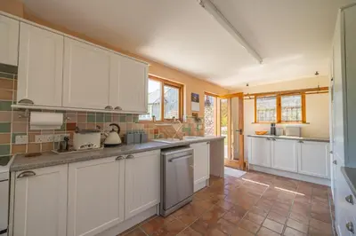 a kitchen with white cabinets and a tile floor at Leighton Banks in Beetham