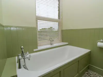 a bath tub in a green bathroom with a window at 28 Rock Villas in Carnforth