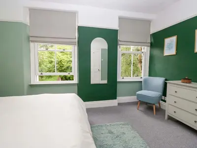 a bedroom with green walls and a bed and a chair at 28 Rock Villas in Carnforth
