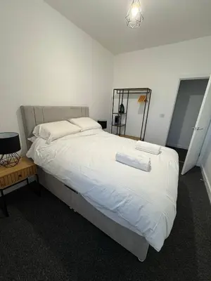 a bedroom with a large bed with white sheets at Homely stay Bootle Liverpool in Litherland
