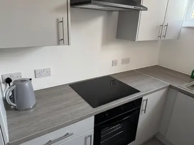 a kitchen with white cabinets and a black stove top oven at Homely stay Bootle Liverpool in Litherland