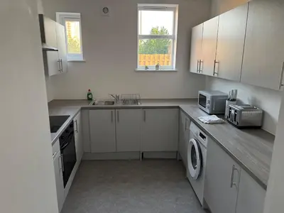 a kitchen with white cabinets and a sink and a microwave at Homely stay Bootle Liverpool in Litherland