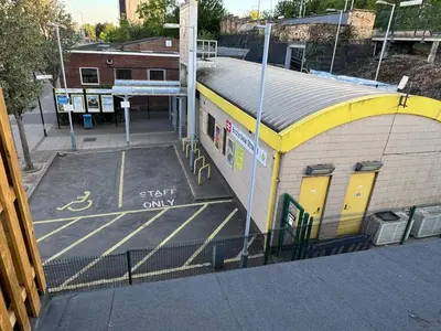 a train station with a building with a parking lot at Homely stay Bootle Liverpool in Litherland