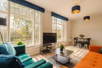 a living room with a couch and a tv at Elysée Suites - Lovely 2 Bed Flat in Southport in Southport