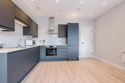 a kitchen with blue cabinets and a wooden floor at Elysée Suites - Lovely 2 Bed Flat in Southport in Southport