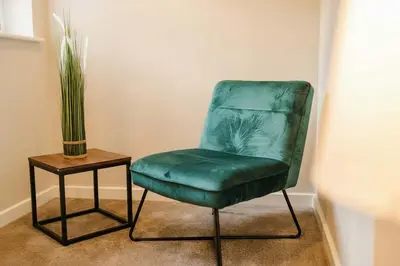 a green chair sitting next to a table with a vase at Elysée Suites - Lovely 2 Bed Flat in Southport in Southport