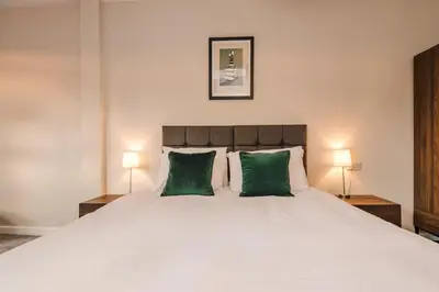 a bedroom with a large white bed with two green pillows at Elysée Suites - Lovely 2 Bed Flat in Southport in Southport