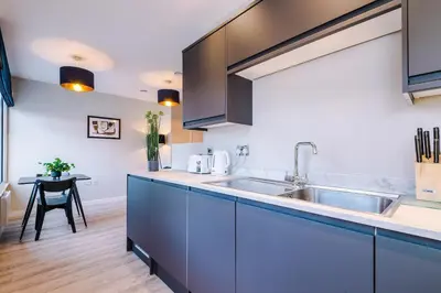 a kitchen with blue cabinets and a sink at Elysée Suites - Modern 1 Bed Flat in Southport in Southport