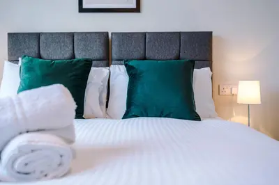 a bedroom with a white bed with green pillows at Elysée Suites - Modern 1 Bed Flat in Southport in Southport