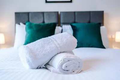 a roll of white towels sitting on a bed at Elysée Suites - Modern 1 Bed Flat in Southport in Southport