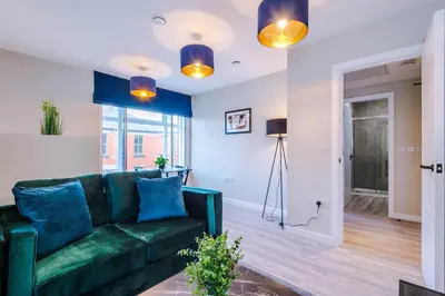 a living room with a green couch and blue pillows at Elysée Suites - Modern 1 Bed Flat in Southport in Southport