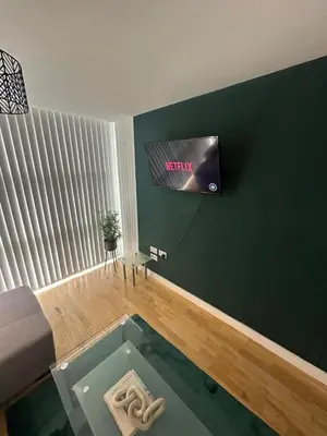 a living room with a tv on a green wall at City View One Bedroom Apartment by StaySavvy Accommodation in Liverpool