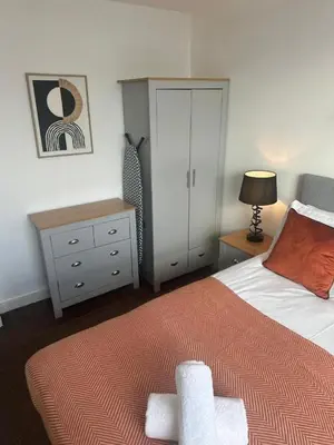 a bedroom with a bed and a dresser and a bed at City View One Bedroom Apartment by StaySavvy Accommodation in Liverpool