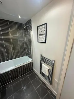 a bathroom with a bath tub and a tile floor at City View One Bedroom Apartment by StaySavvy Accommodation in Liverpool