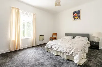 a white bedroom with a bed and a window at Olive Guest House in Bolton