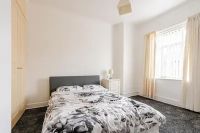 a white bedroom with a bed and a window at Olive Guest House in Bolton