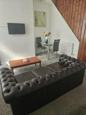 a living room with a leather couch and a table at Olive Guest House in Bolton