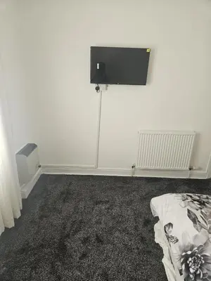 a white room with a tv on the wall at Olive Guest House in Bolton