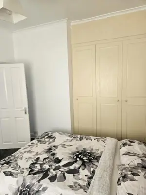 a bedroom with a bed and a white cabinet at Olive Guest House in Bolton