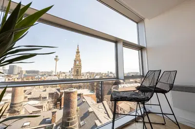 a balcony with two chairs and a view of a city at Stunning Skyline Liverpool Apartment with Parking in Liverpool