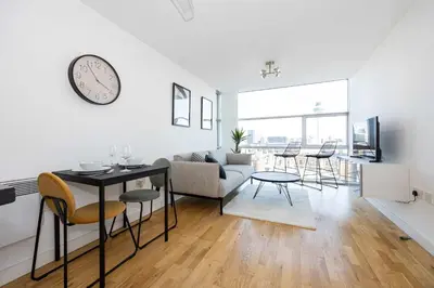 a living room with a table and chairs and a clock at Stunning Skyline Liverpool Apartment with Parking in Liverpool