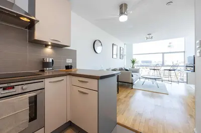 a kitchen with a counter top and a living room at Stunning Skyline Liverpool Apartment with Parking in Liverpool