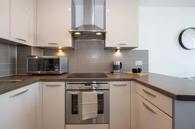 a kitchen with white cabinets and a stove top oven at Stunning Skyline Liverpool Apartment with Parking in Liverpool